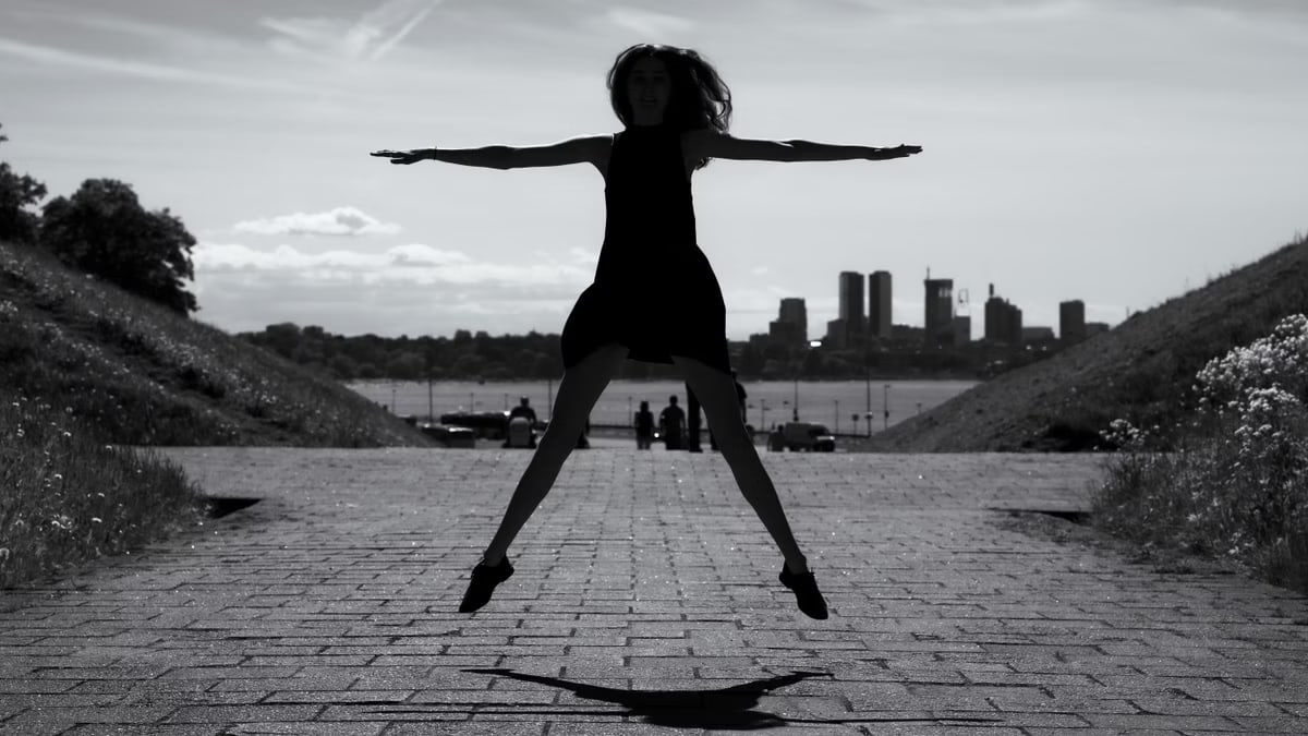 A dynamic black and white silhouette of a woman jumping with arms outstretched in Tallinn, Estonia.